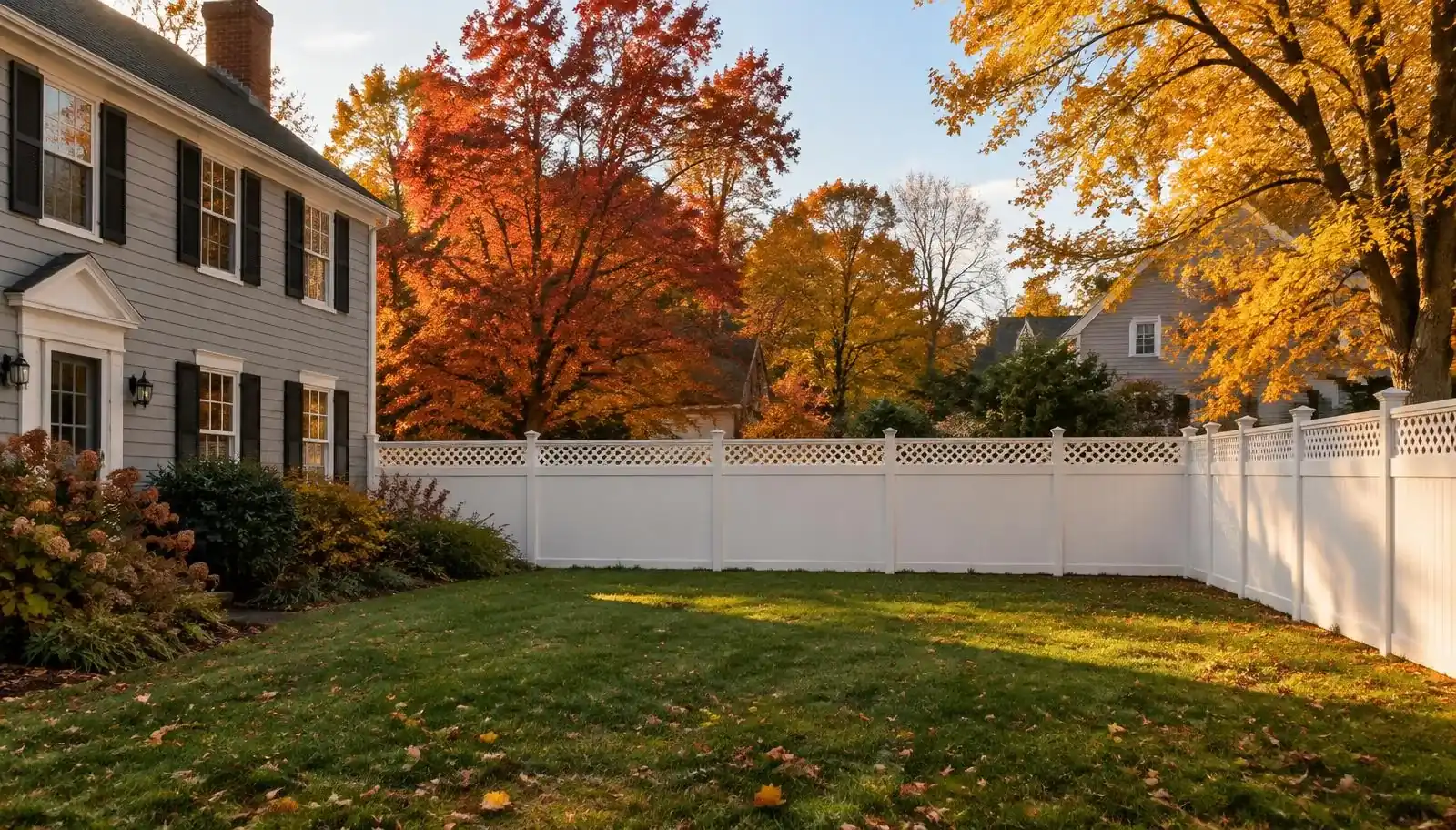 White vinyl privacy fence with lattice top around a suburban New England backyard in Greater Boston in fall