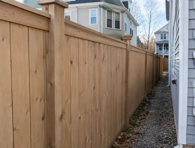 Wood privacy fence along a narrow lot beside a two-family house in the Boston area